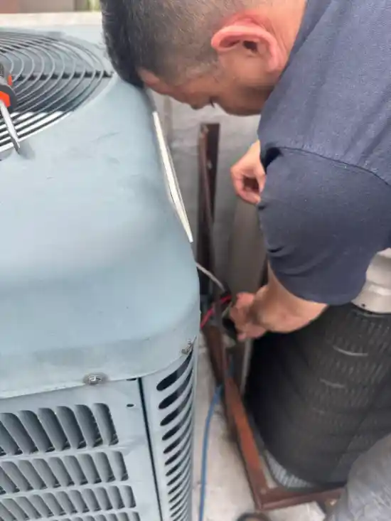 Technician servicing outdoor AC condenser unit