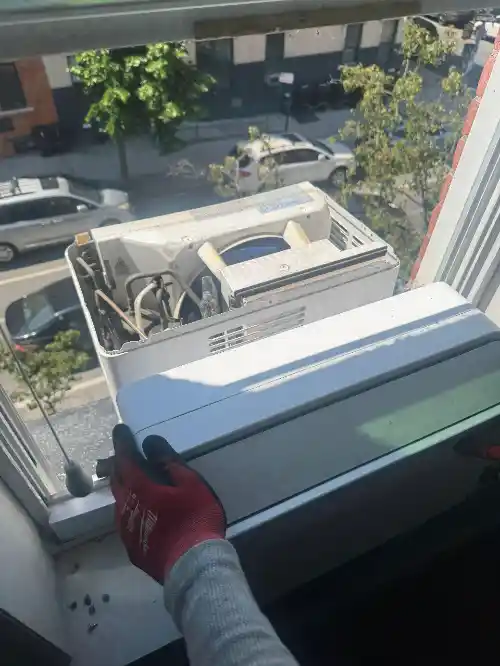 Technician performing window air conditioner repair work